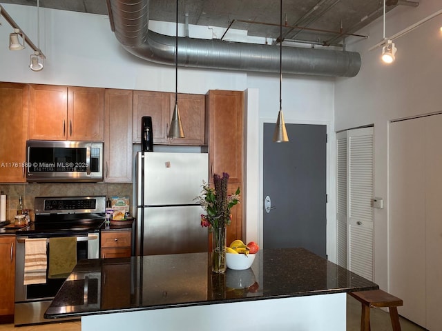 kitchen with decorative backsplash, brown cabinets, appliances with stainless steel finishes, and a towering ceiling