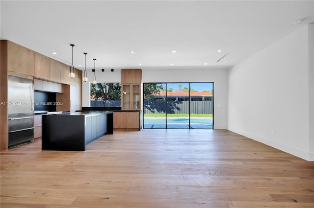 kitchen with stainless steel built in fridge, modern cabinets, open floor plan, and light wood-style flooring