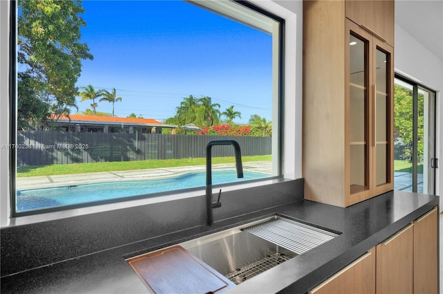 interior space featuring a sink, glass insert cabinets, and dark countertops