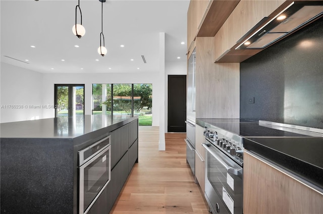 kitchen featuring modern cabinets, high end stainless steel range oven, dark countertops, recessed lighting, and light wood finished floors