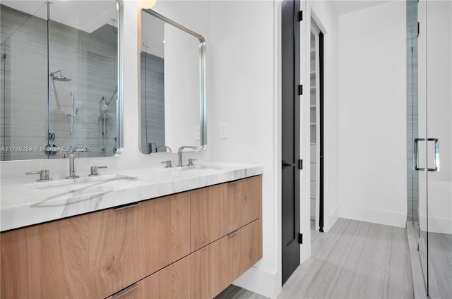 bathroom featuring a sink, baseboards, a stall shower, and double vanity