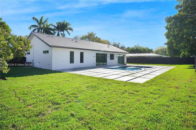 rear view of house featuring stucco siding, fence, a lawn, and a patio area