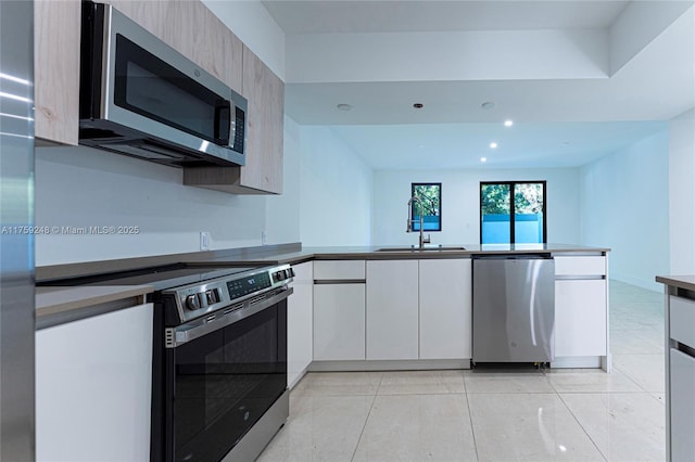 kitchen with a peninsula, stainless steel appliances, modern cabinets, and a sink