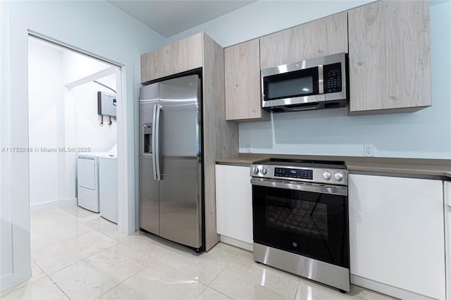 kitchen featuring washing machine and clothes dryer, water heater, appliances with stainless steel finishes, dark countertops, and modern cabinets