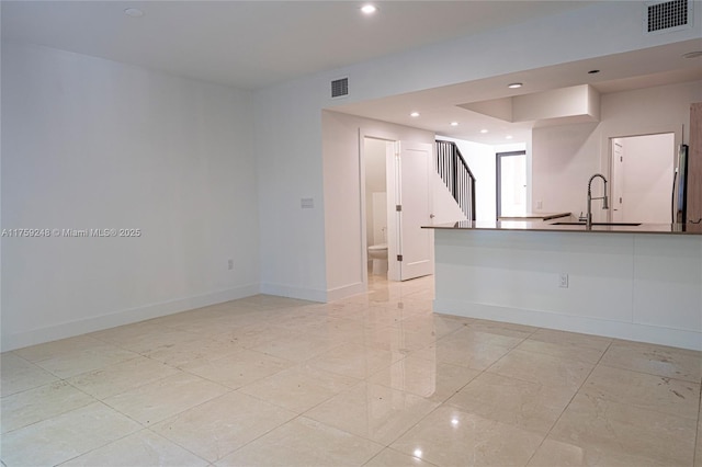 interior space with baseboards, visible vents, and a sink