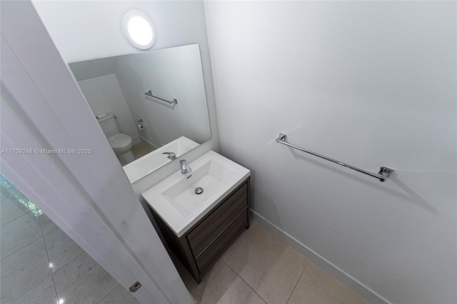 half bath with baseboards, toilet, vanity, and tile patterned flooring