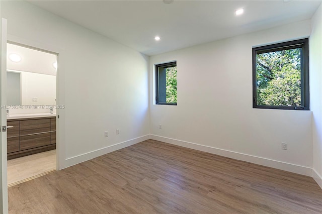 unfurnished bedroom featuring multiple windows, baseboards, and light wood-style floors