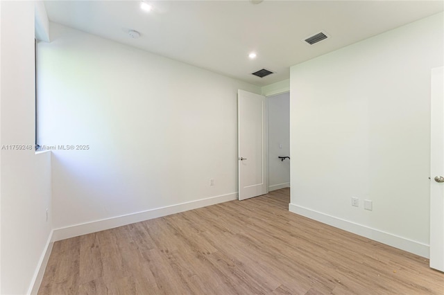 empty room featuring light wood-type flooring, visible vents, baseboards, and recessed lighting