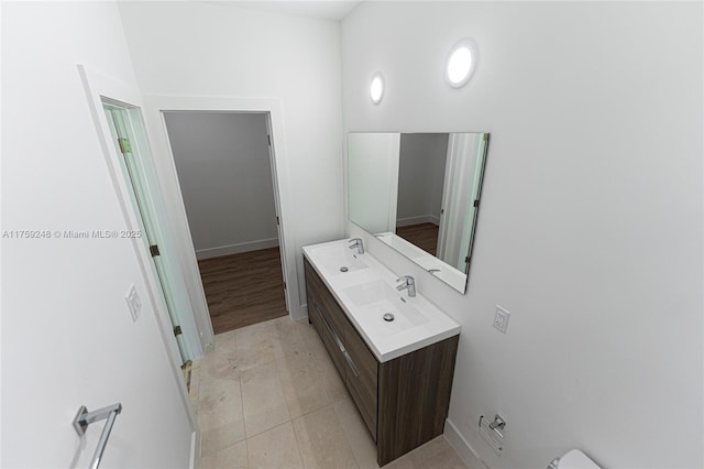 bathroom with double vanity, vaulted ceiling, tile patterned floors, and a sink