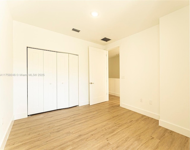 unfurnished bedroom featuring visible vents, baseboards, a closet, and light wood finished floors