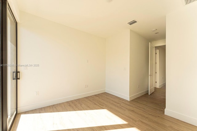 unfurnished room featuring visible vents, light wood-style flooring, and baseboards