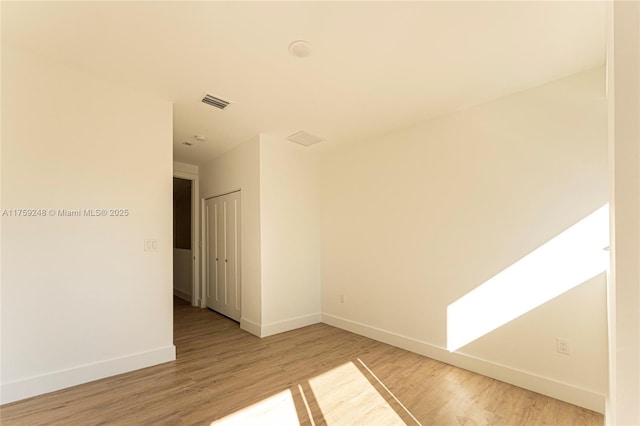 spare room with visible vents, light wood-style floors, and baseboards