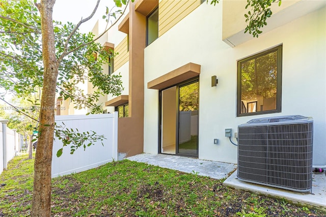 exterior space with stucco siding, central AC unit, and fence