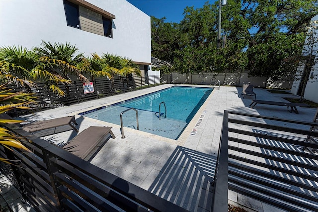 community pool with a patio and fence