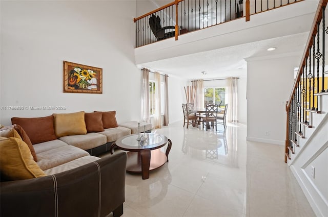 living room with stairs, light tile patterned floors, baseboards, and a towering ceiling