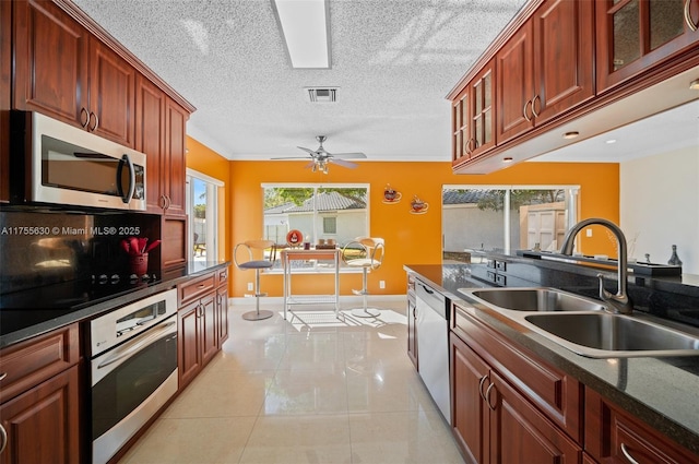 kitchen with visible vents, a sink, dark countertops, stainless steel appliances, and light tile patterned floors