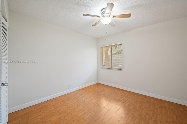 spare room with baseboards, a textured ceiling, light wood-type flooring, and a ceiling fan