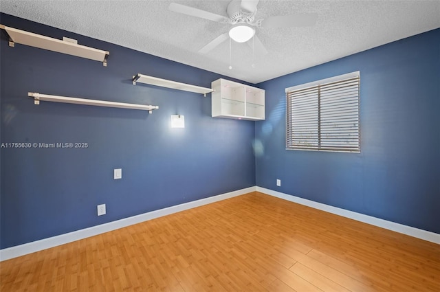 empty room featuring ceiling fan, baseboards, a textured ceiling, and wood finished floors