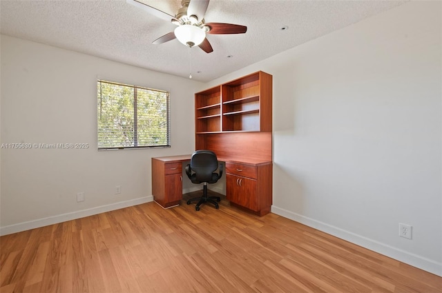 unfurnished office with a ceiling fan, baseboards, light wood-type flooring, and a textured ceiling