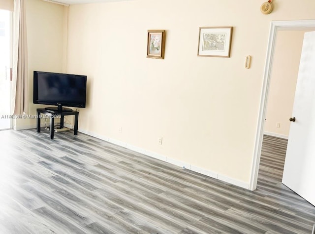 unfurnished living room with baseboards and wood finished floors