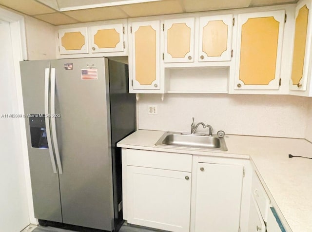 kitchen featuring a sink, light countertops, stainless steel refrigerator with ice dispenser, white cabinetry, and open shelves