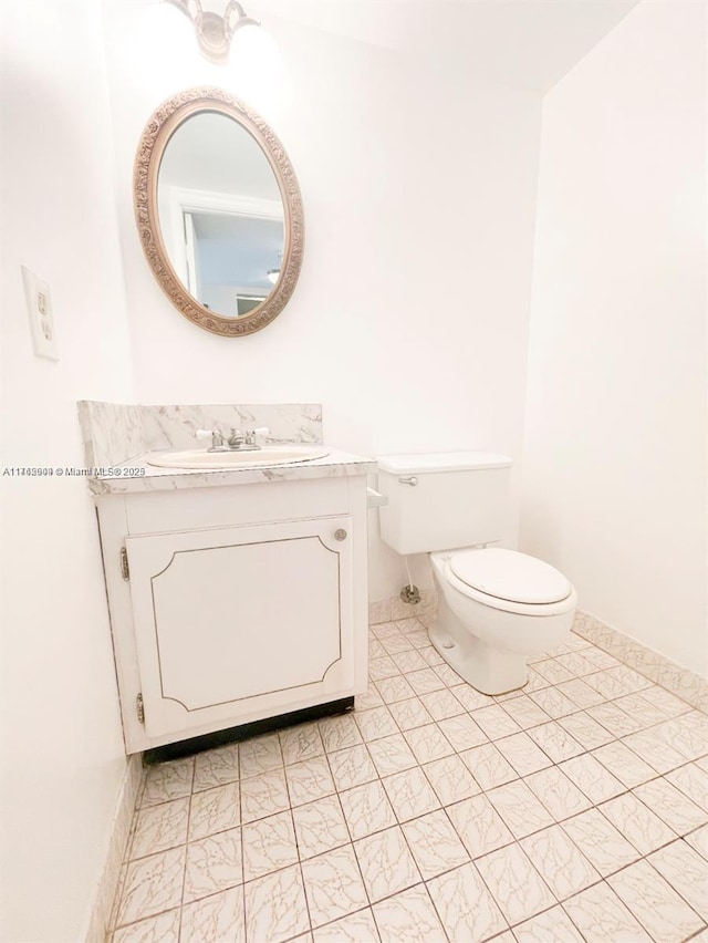 bathroom featuring vanity, toilet, and baseboards