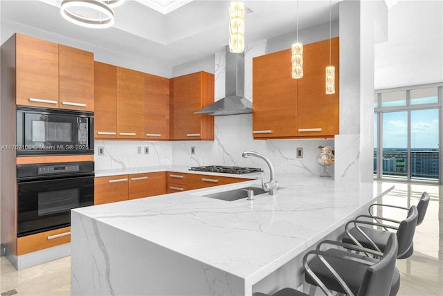 3535 S Ocean Dr Unit 2606, Hollywood, FL 33019 - kitchen featuring black appliances, wall chimney exhaust hood, a peninsula, brown cabinetry, and light stone counters