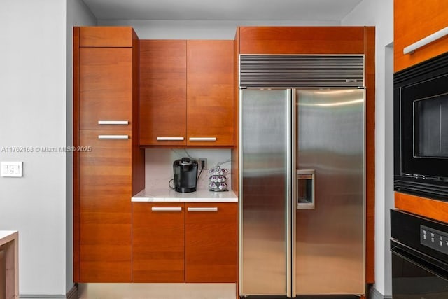 kitchen featuring brown cabinets, black appliances, light countertops, and modern cabinets