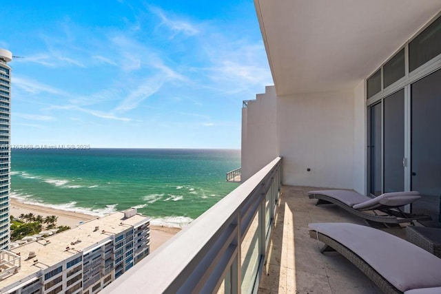 balcony with a water view and a view of the beach