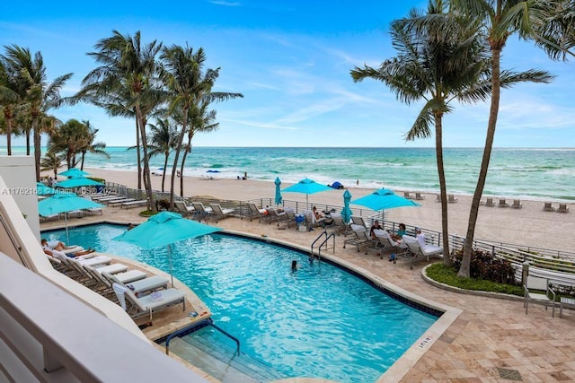 pool featuring a patio area, a beach view, and a water view