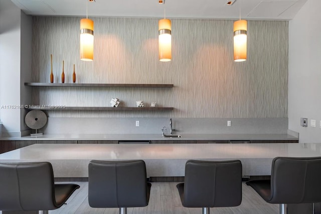 bar with pendant lighting, wood finished floors, and a sink