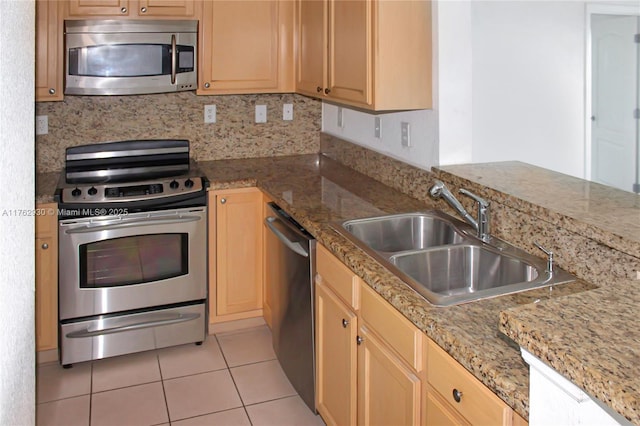 kitchen with tasteful backsplash, light stone countertops, appliances with stainless steel finishes, light tile patterned flooring, and a sink