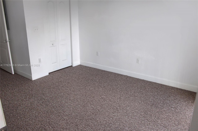 unfurnished bedroom with baseboards and dark colored carpet