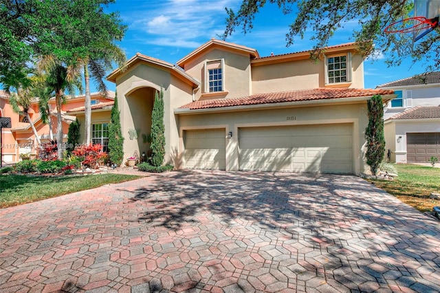 mediterranean / spanish house with stucco siding, a tile roof, and decorative driveway