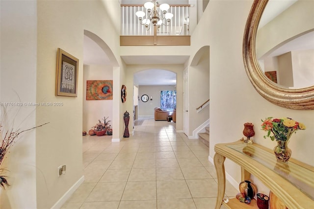 hallway with baseboards, stairway, arched walkways, a high ceiling, and light tile patterned flooring