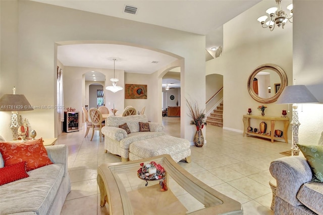 living room featuring visible vents, beverage cooler, stairway, light tile patterned floors, and arched walkways