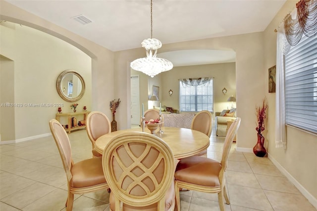 dining room featuring visible vents, baseboards, a chandelier, light tile patterned floors, and arched walkways