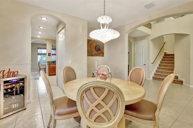 dining area featuring visible vents, beverage cooler, light tile patterned flooring, a chandelier, and stairs