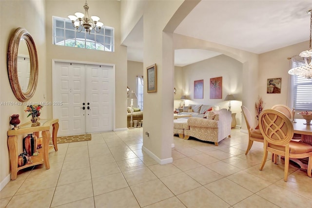 entryway with light tile patterned floors, a notable chandelier, arched walkways, and baseboards