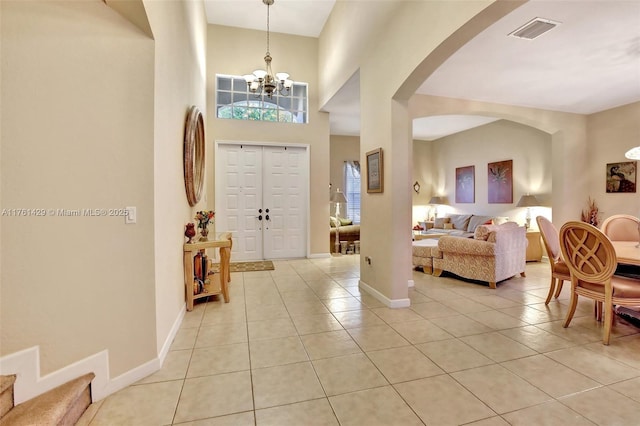 foyer entrance with light tile patterned flooring, visible vents, baseboards, and an inviting chandelier