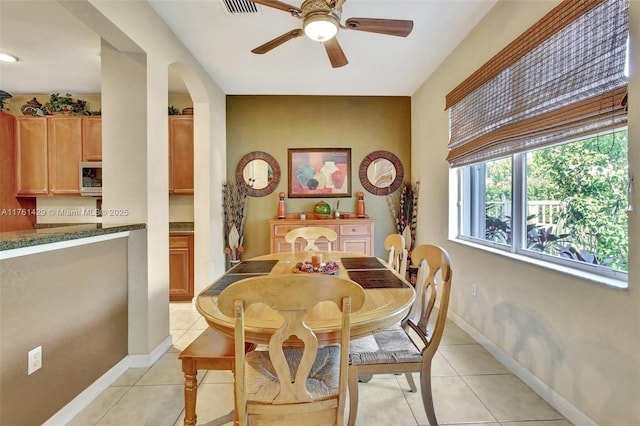 dining area featuring visible vents, arched walkways, light tile patterned floors, baseboards, and ceiling fan