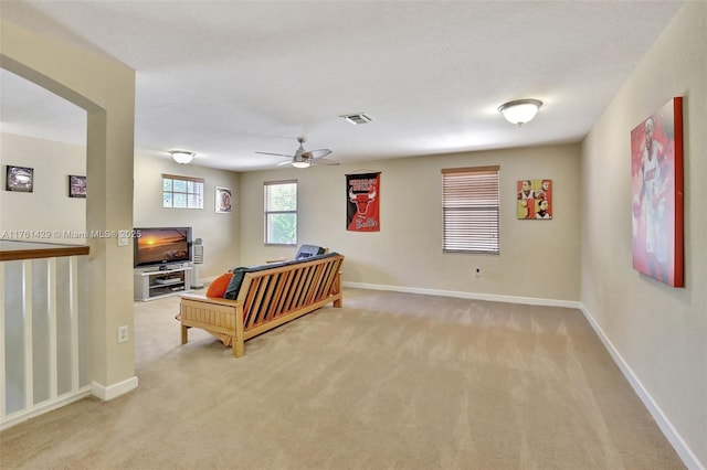 interior space with visible vents, light colored carpet, a ceiling fan, and baseboards