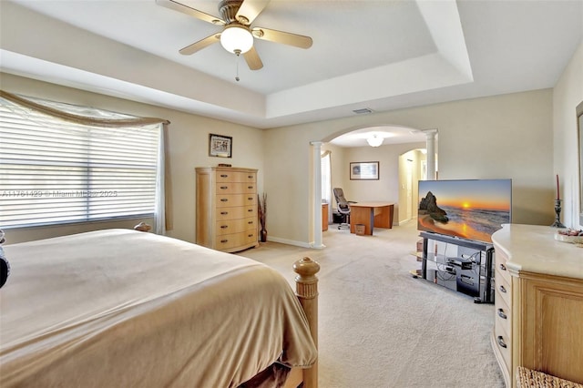 bedroom featuring visible vents, ornate columns, arched walkways, light carpet, and a raised ceiling