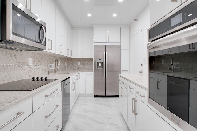 kitchen featuring light stone counters, white cabinetry, black appliances, and a sink