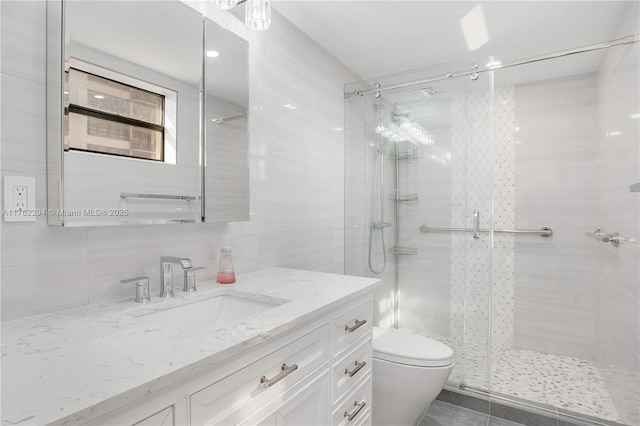 bathroom featuring toilet, a stall shower, tasteful backsplash, tile walls, and vanity