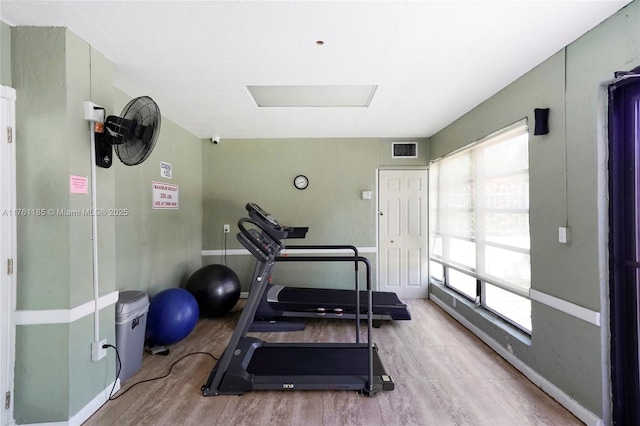 workout room with wood finished floors, visible vents, and baseboards