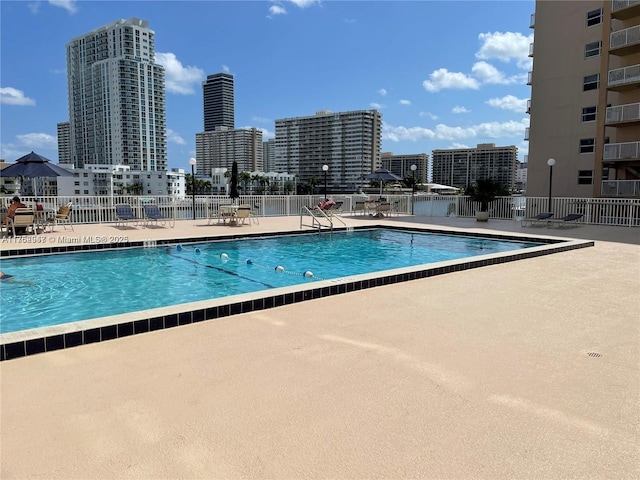 pool with a city view, a patio area, and fence