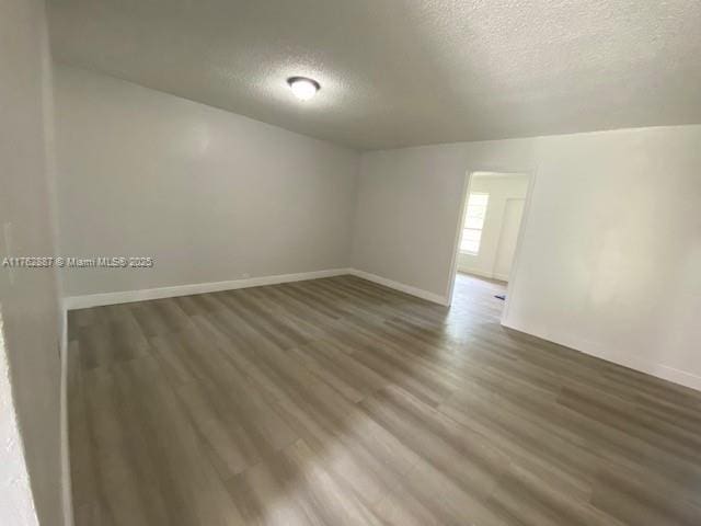 empty room with baseboards, a textured ceiling, and wood finished floors