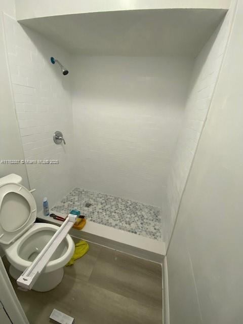 full bathroom featuring a shower stall and toilet