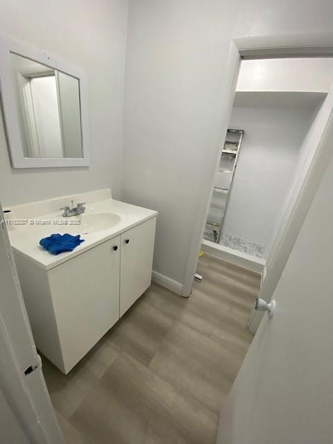 bathroom featuring vanity, wood finished floors, and baseboards